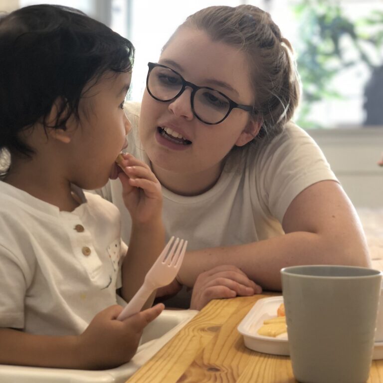 a kid eating with teacher beside